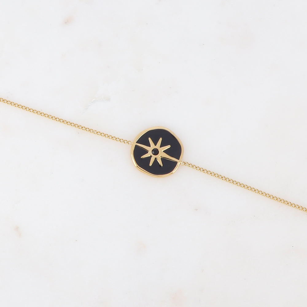 Bracelet chaîne doré composé d'une médaille étoile émaillé noir serti d'un strass noir